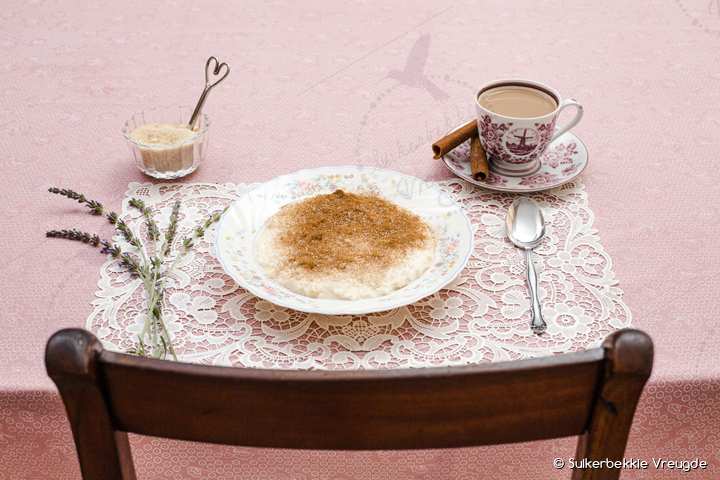 'n Gedekte tafel met melkkos, 'n koppie koffie en laventel op 'n kantdoek